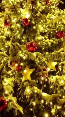 Etrafı parlak ışıklar ve renkli süslemelerle süslenmiş güzel dekore edilmiş bir Noel ağacı.