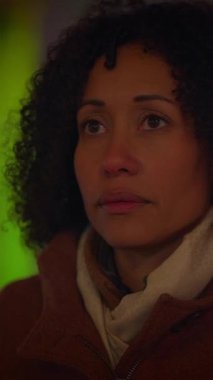 Kentsel bir ortamda, atkısı olan bir kadın derin duygular ifade ederek düşünceli bir şekilde uzaklara bakar.