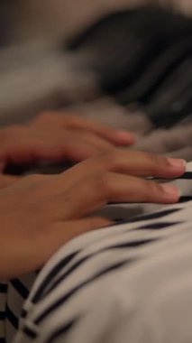 Güzel çizgili kumaşın üzerinde nazikçe dinlenen bir elin yakın çekimi sıcaklık ve derin bir rahatlık hissi veriyor.