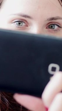 Modern bağlantıyı ve etkileşimi vurgulayan akıllı telefonuna odaklanmış genç bir kadının yakın çekimi.