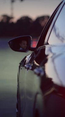 Yan aynasında güzel bir yansıması olan şık bir arabayı tasvir eden sakin bir akşam sahnesi.