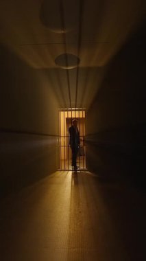Ürkütücü ve perili bir koridor sadece tek bir loş ışık kaynağı tarafından aydınlatılan ağır parmaklıklı bir kapıya doğru uzanıyor.