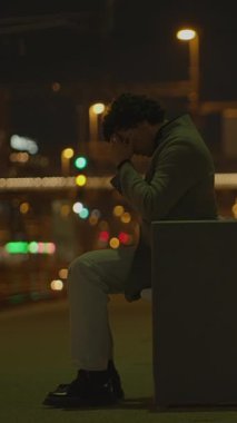 Yalnız bir birey, sakin gece saatlerinde loş bir kentsel çevreye sessizce yansıyor.