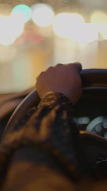 Güçlü bir el direksiyonu sıkıca kavrıyor, gece bulanık şehir ışıklarında aracı ustalıkla yönlendiriyor.