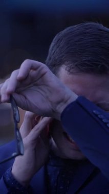 Uygun bir adam, bir telefon görüşmesi sırasında gergin ve endişeli görünür. Dramatik bir şehir ortamında duygularını gösterir.