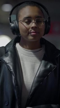 Düşük ışıkta kulaklık takan gölgeli bir figür, etrafında entrika ve derin bir gizem yaratıyor.