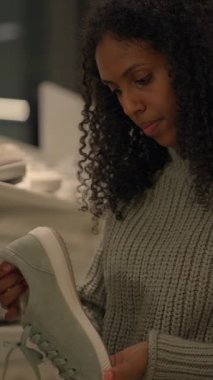 Bir kadın modaya uygun, modern bir perakende pazarında alışveriş yaparken şık bir spor ayakkabısını dikkatlice inceler.