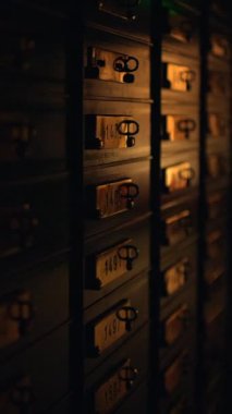 Loş bir ambiyansı olan eski bir dosya dolabı. Eşsiz anahtarlarla gelen birkaç çekmeceyi gösteriyor.