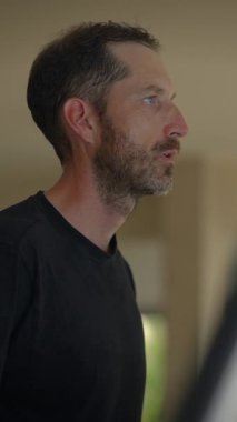Bir adam düşünceli bir profil pozisyonunda duruyor, sakin bir ortamda derin düşüncelere dalmış.