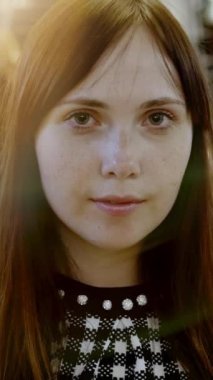 Uzun dalgalı saçlı, yumuşak, doğal, sıcak bir ışıkla yakalanmış güzel sakin bir genç kadın portresi.