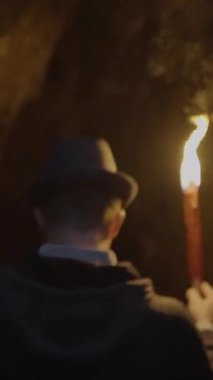 Bir insan kendinden emin bir şekilde yanan bir meşale tutar, karanlığı aydınlatır ve etrafına sıcak bir ışık saçar.