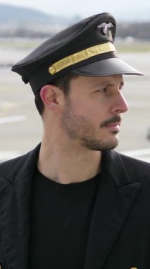 Üniformalı kendinden emin bir pilot havaalanında gururla duruyor, yaklaşan uçuş için tamamen hazır.