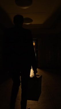 Hafif aydınlık bir koridorun sakin ama ürkünç bir sahnesi önümüzde yumuşak, ışıldayan bir kapı aralığına doğru gidiyor.