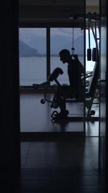 Güzel manzaralı modern bir spor salonunda egzersiz yapan birinin etkileyici bir silueti.