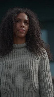 Güzel kıvırcık saçlı kendine güvenen bir kadın düşünceli bir şekilde uzaklığa bakar.