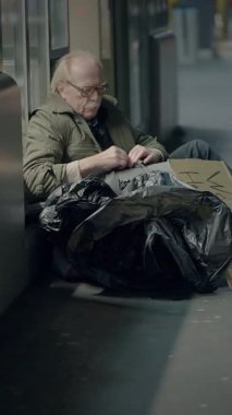 Halka açık bir alanda yalnız oturan evsiz bir adamın dokunaklı görüntüsü yalnızlığı ve zorlukları yansıtıyor..