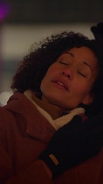 Bir kadın, serin bir akşamda hoş bir neşe ve sıcaklık hisseder. Etrafı güzel, canlı ışıklarla çevrilidir.