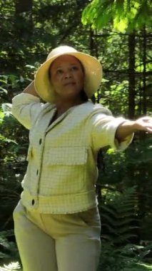 Bir kadın zarif bir şekilde canlı, yemyeşil bir ortamda poz verir. Etrafa güven ve iç huzuru yayar.