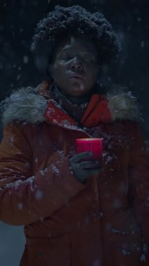 Yumuşak kar dinginliğinde, yalnız bir figür titreyen bir mum tutar, sıcaklık ve içgözlem çağrıştırır.