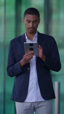 Genç bir adam şık ve çağdaş bir ortamda bulunurken tabletle aktif olarak meşgul.