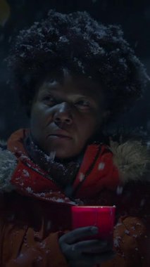 Derin düşüncelere dalmış biri, kalın giysiler içinde, dışarıda, güzel kar altında huzurlu bir anın tadını çıkarıyor.