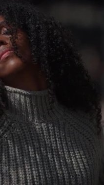 Bir kadının yakın çekimi kıvırcık saçlar canlı bir şehir zeminine karşı, kentsel tarzı ve kabiliyeti yakalıyor.