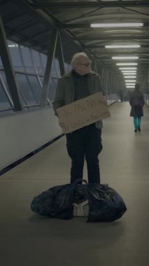 Bir birey dar bir koridorda karton bir çantanın üzerinde duruyor, yalnızlık ve kentsel yaşamın derin temalarını çağrıştırıyor.