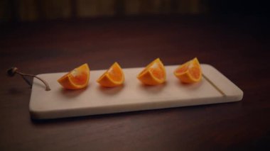 Canlı portakal dilimleri, yemek fotoğrafçılığı için mükemmel bir minimalist kesim tahtasına yerleştirilmiş.