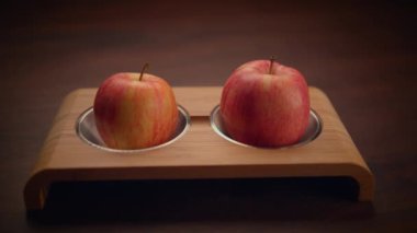 İki canlı kırmızı elma şık bir ahşap tutacakta güzelce sergilenir. Taze meyve şekillendirme için idealdir.
