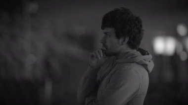 Derin düşüncelere dalmış yalnız bir figür bulanık, tek renkli bir şehir ortamında güzel bir şekilde yakalanır.