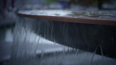 Büyüleyici ve sakin bir su manzarası çağdaş bir çeşmenin kenarından yavaşça ve nazikçe dökülüyor.