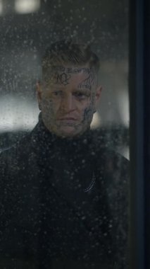 Düşünceli ve düşünceli bir figür yağmurlu bir pencereden derin derin bakar, sayısız duyguyu harekete geçirir.