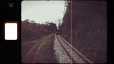 Yeşillik ve sisli arazide dolaşan demiryolu raylarını gösteren nostaljik bir klasik manzara.