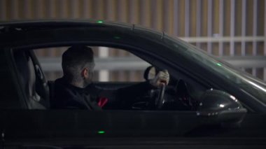 Zahmetsizce özgüvenli bir beyefendi, lüks bir arabada oturuyor, gece yolculuğu sırasında hem zarafet hem de gizem saçıyor.