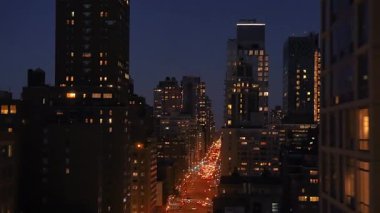 Parlak şehir gökdelenleri ve parıldayan ışıklarla dolu hareketli bir şehir caddesinin güzel bir gece manzarası..