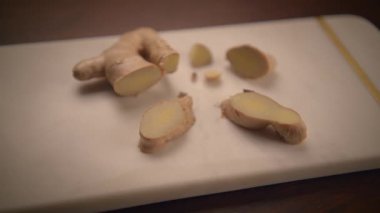 Kırsal kesim tahtasının üzerinde taze dilimlenmiş zencefil kökü, eşsiz dokusunu ve tazeliğini sergiliyor.