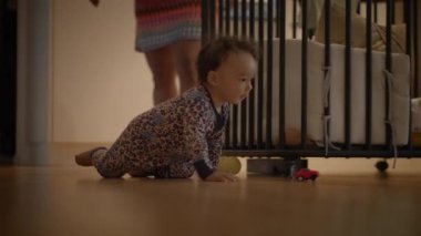 Sevimli bir bebek yerde sürünüyor, oyunu davet eden renkli oyuncaklarla dolu sıcak bir alanı keşfediyor.
