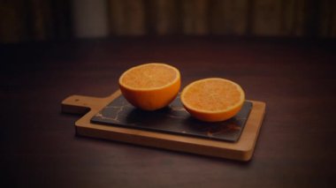 İkiye bölünmüş canlı portakallar, güzel bir şekilde sulu posalarını sergiliyorlar, şık bir ahşap tahta üzerinde sergileniyorlar.