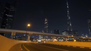 Dubai şehir merkezindeki gece manzarasında gökdelenler, otoyollar ve şehir ışıkları modern titreşimler sergiliyor.