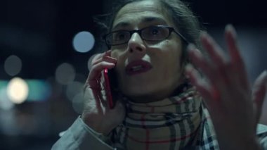 Canlı bir şehir ortamında canlı bir şekilde cep telefonuyla konuşan bir kadın çeşitli duygular sergiliyor.