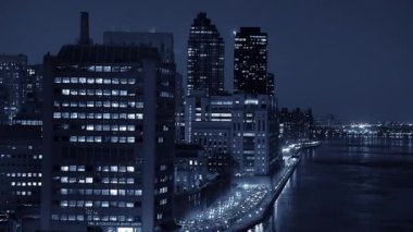 Büyüleyici bir gece manzarası nehri kaplayan parlayan binalarla dolu canlı bir şehir silueti sergiliyor.