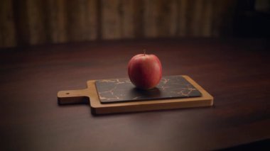 Canlı, parlak kırmızı bir elma güzel bir kırsal kesim tahtasının üzerinde duruyor. Büyüleyici yemek fotoğrafçılığı için gerçekten ideal.