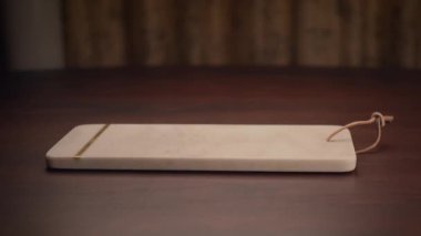 Bu parlak ahşap bir tahta kesim tahtası. Minimalist bir tasarımı ve deri bir kravatı var.