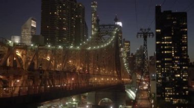 Queensboro Köprüsü 'nün göz kamaştırıcı gece manzarasını tecrübe edin alacakaranlıkta ışıl ışıl parlayan bir şehrin siluetine karşı aydınlandı.