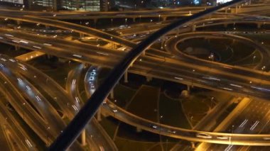 Geceleri aydınlatılan ve kentsel trafik akışı ve altyapıyı gösteren karmaşık bir otoyol ağı.