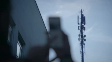 Bir kullanıcı, günlük yaşamda teknolojinin rolünü vurgulayan, kentsel bir ortamda akıllı bir telefonla etkileşim kurar