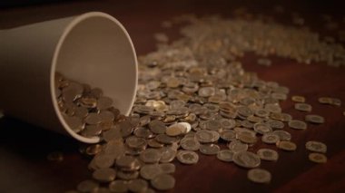 Bir bardaktan dökülen parlak bozuk paralar büyüleyici bir servet ve şans karışımı sergiliyor.