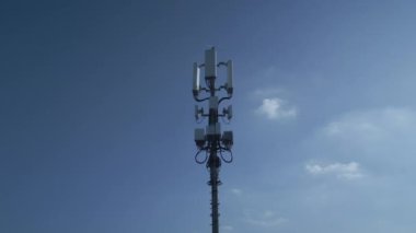 Uzun bir hücresel iletişim kulesi, açık mavi gökyüzünün altında modern telekom sistemlerinin kilit bir parçası olarak yükseliyor.