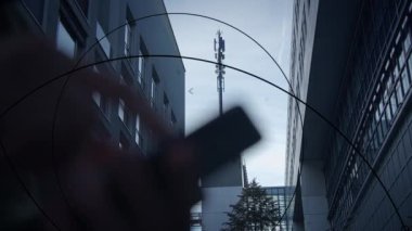 Çağdaş bir şehir sokağı, modern binaların arka planına kurulmuş önemli bir iletişim antenine sahiptir.