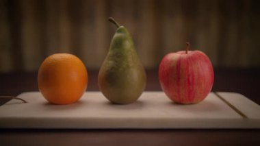 Renkli, taze portakallar, sulu armutlar ve kırsal ahşap bir tahtanın üzerine yerleştirilmiş çıtır çıtır elmalar.